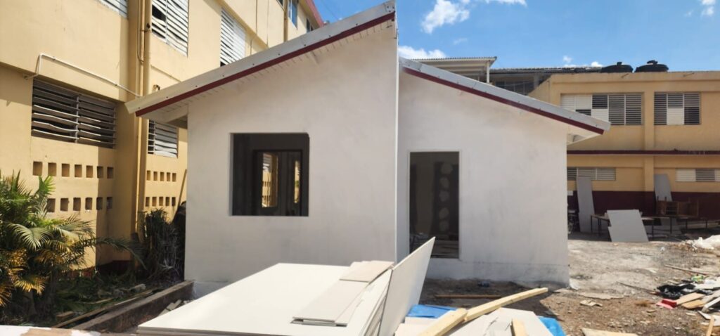 New single storey classroom block with rendered walls beside a school building