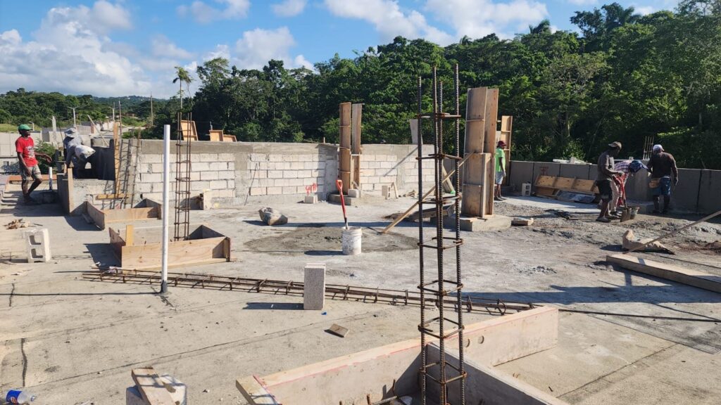 Workers setting out columns and block work on a rooftop extension