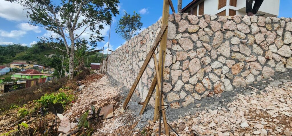 Stone retaining wall holding back a hillside above a playing field